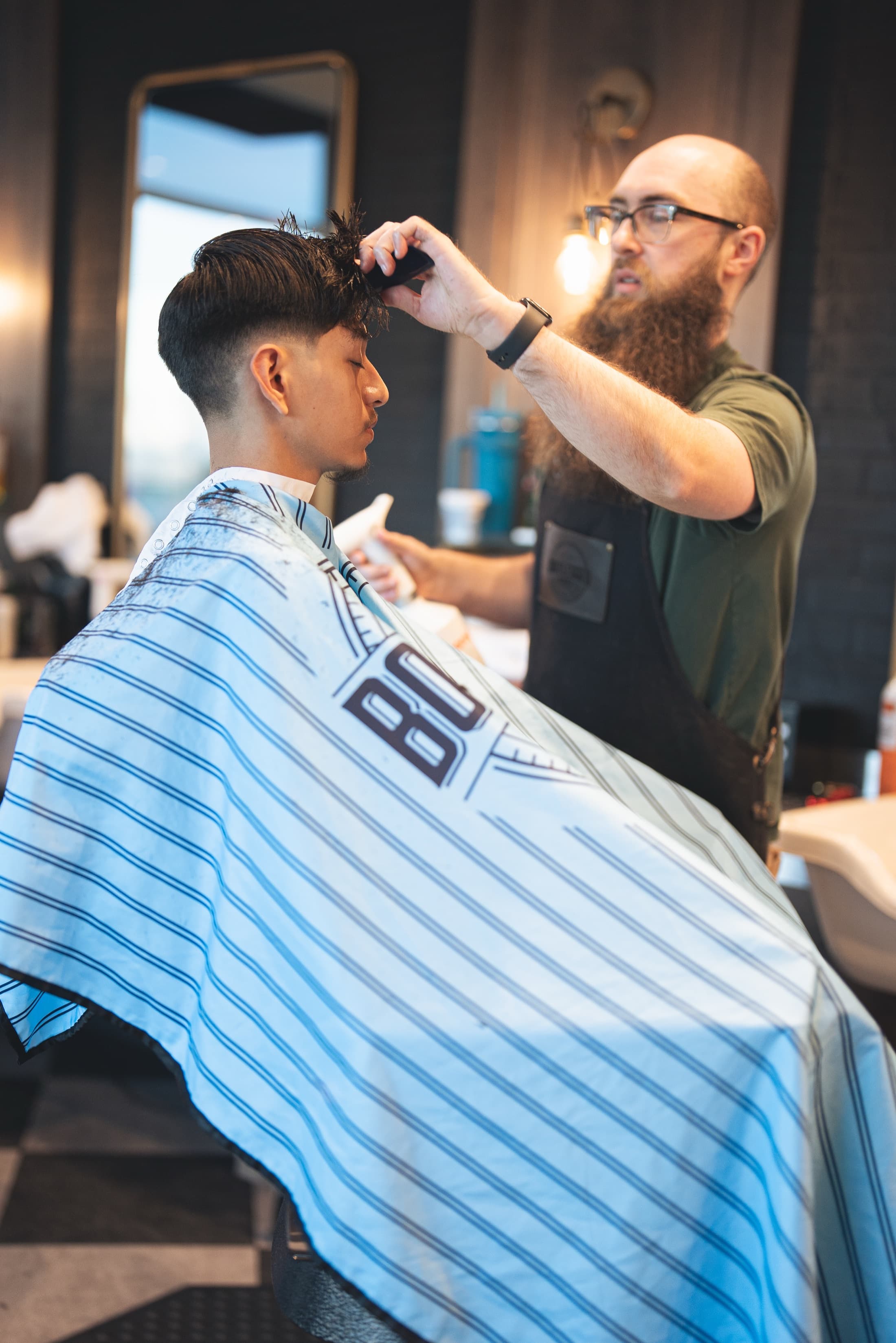 A Bootlegged barber combing and sectioning a client's hair